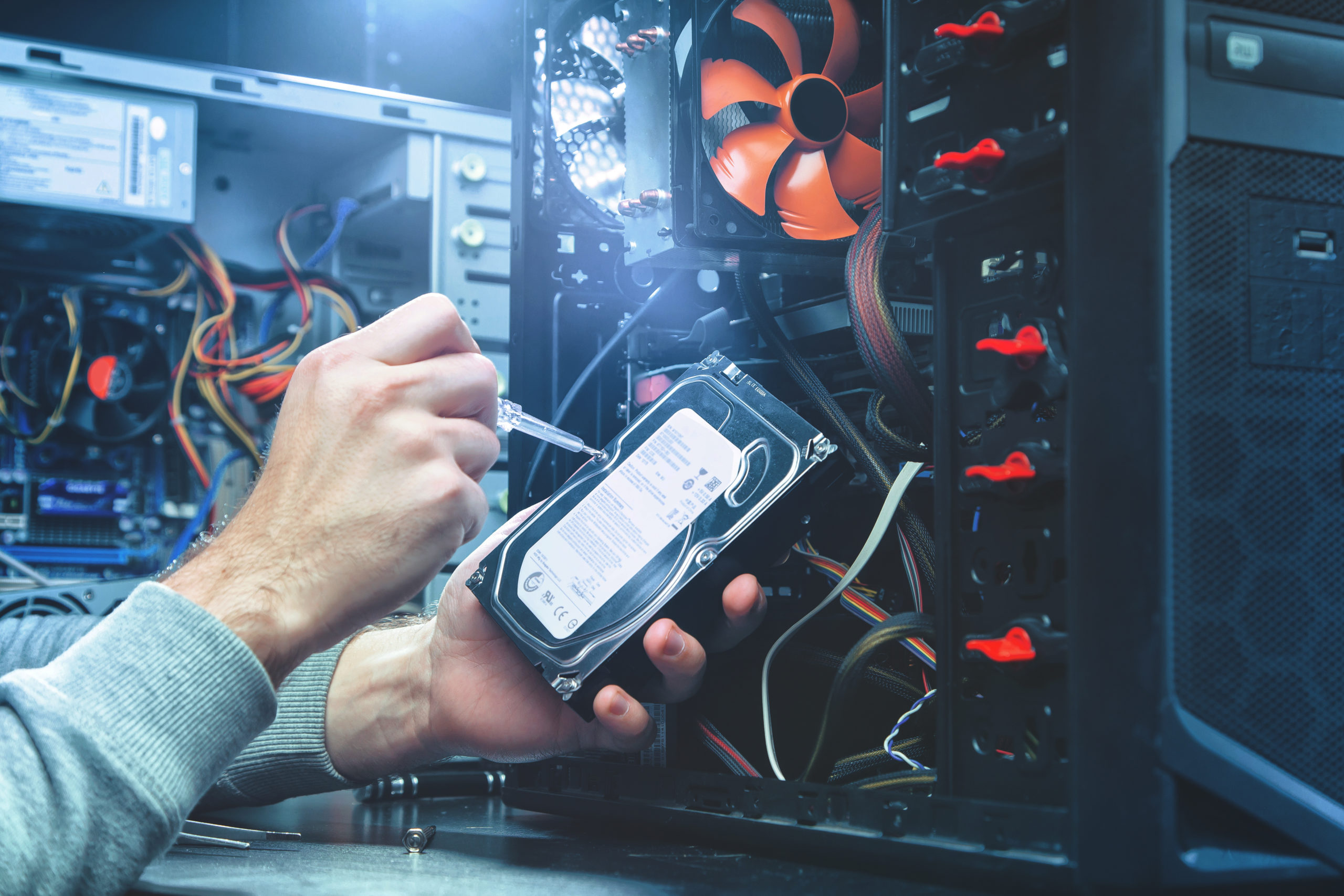Technician repairing a computer, the process of replacing components on the motherboard. The technician hold the screwdriver for repairing PC. The concept of computer hardware, repairing, upgrade Reparatur durch Technogroup