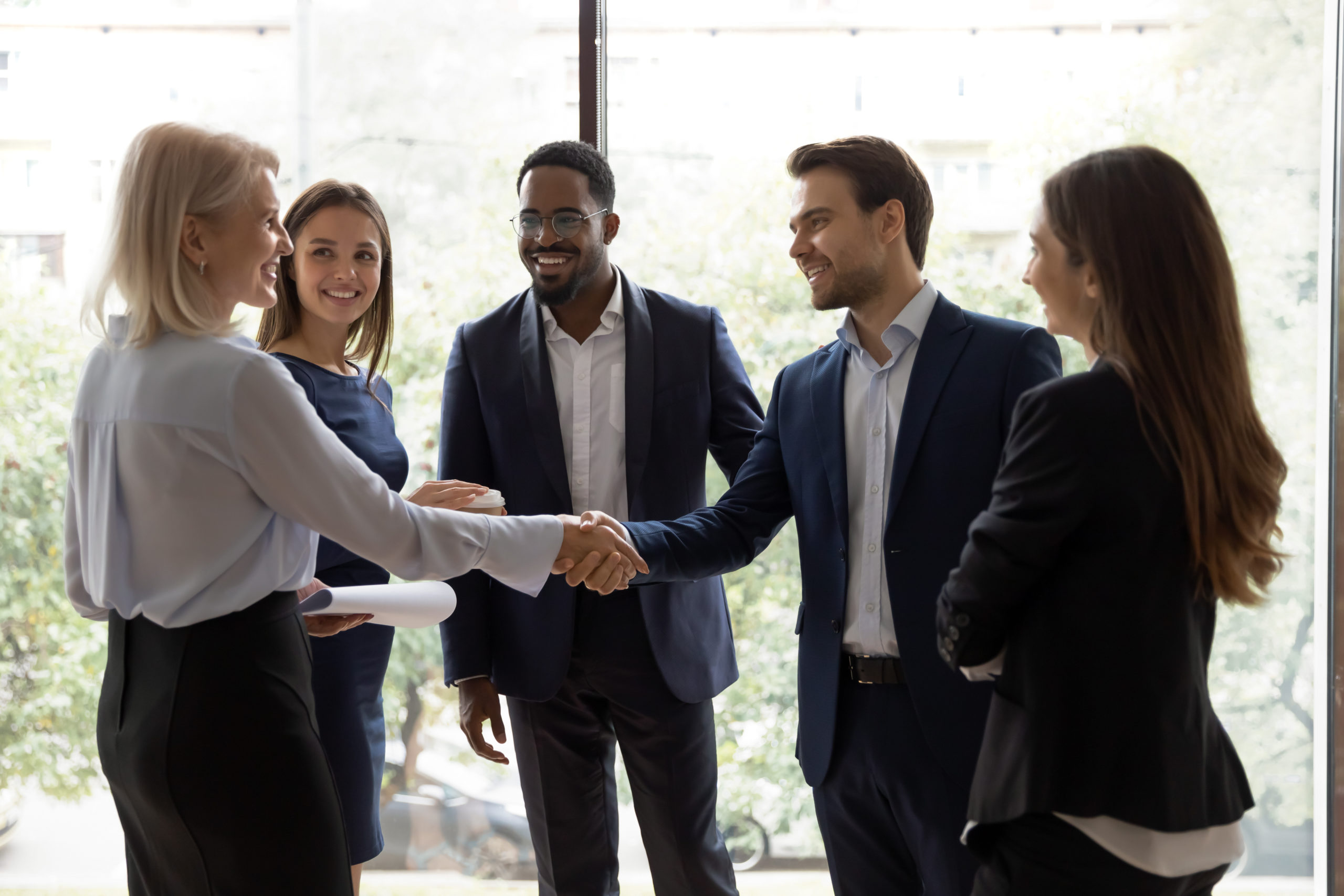 Young team leader greeting elder female employee at lunch break